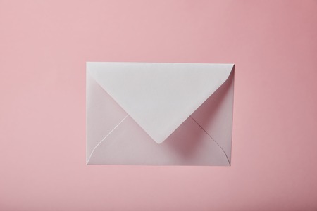 white and empty envelope on pink background with copy spaceの写真素材