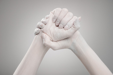 cropped view of female hands painted in white with clenched hands on greyの写真素材