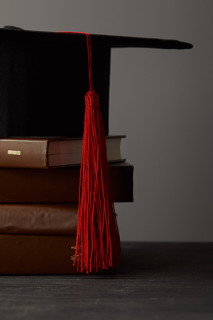 Brown books and academic cap with red tassel isolated on greyの写真素材