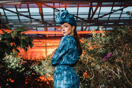 Gorgeous young woman in blue dress in turban in orangeryの写真素材