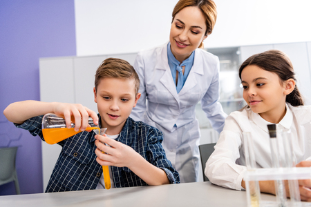 Chemistry teacher looking at pupil with beaker and flask in classroomの写真素材