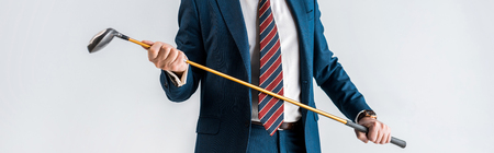 panoramic shot of mature man in suit holding golf club isolated on greyの写真素材