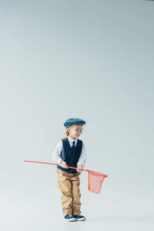 adorable and blonde kid in retro vest and cap holding butterfly netの写真素材