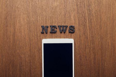 top view of digital tablet with blank screen near news letteringの写真素材