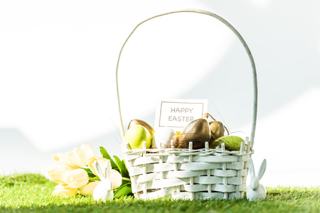 straw basket with colorful easter eggs, happy easter card, tulips and decorative rabbit on whiteの写真素材