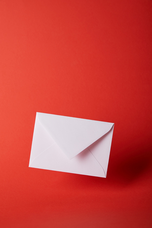 white and empty envelope on bright red background with copy spaceの写真素材