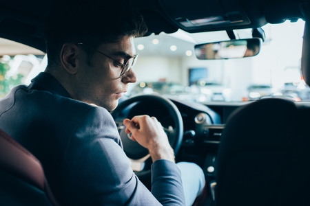 selective focus of successful man in glasses sitting in automobileの写真素材