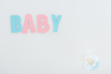 top view of pacifier and pink and blue baby lettering isolated on white with copy spaceの写真素材