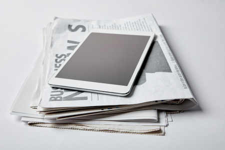 digital tablet with blank screen near business newspapers with articles on whiteの写真素材
