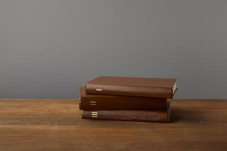 Three brown books on textured wooden surface on greyの写真素材