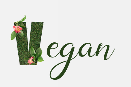 top view of green vegan lettering with leaves and alstromeria flowers isolated on whiteの写真素材