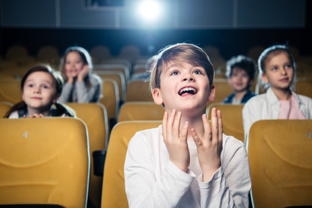 amused emotional boy watching movie together with multicultural friendsの写真素材