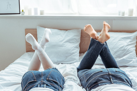 cropped view of man and woman in jeans and shorts in bedroom
