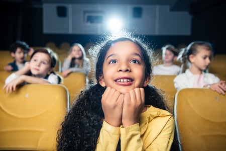 selective focus of adorable african american girl watching movie in cinema together with friendsの写真素材