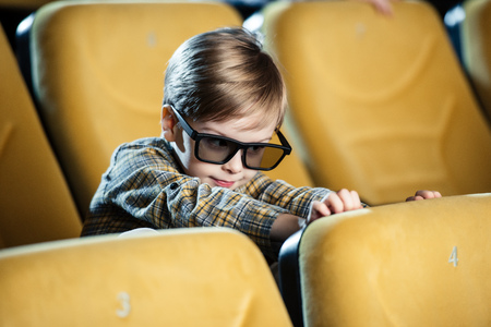 cute smiling boy in 3d glasses sitting in comfortable cinema seatの写真素材