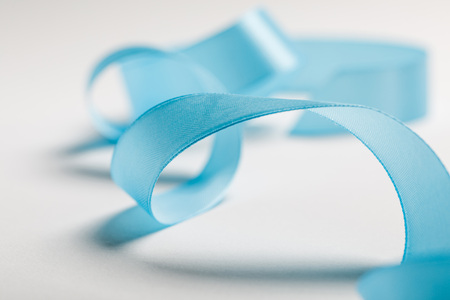 close up of wavy blue satin ribbon on grey backgroundの写真素材