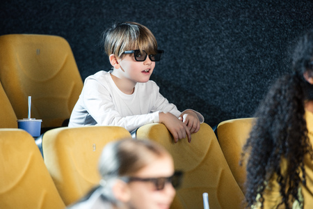 selective focus of cute boy in 3d glasses spending time in cinema together with multicultural...