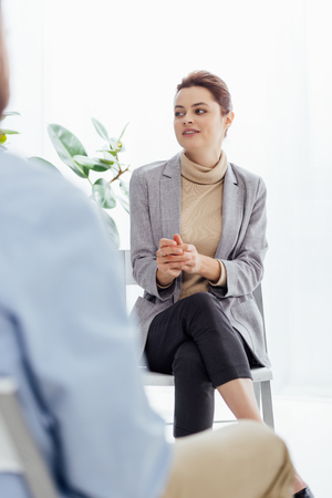 selective focus of woman in formal wear sitting and looking away during therapy sessionの写真素材