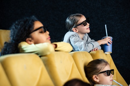 selective focus of cute multicultural friends watching movie in cinema together