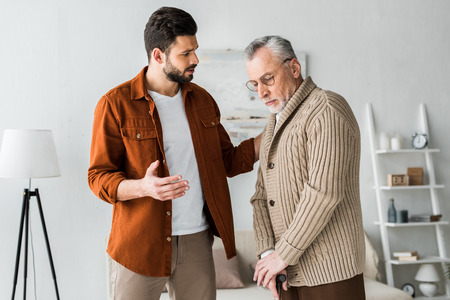 handsome bearded man gesturing while looking at sad senior fatherの写真素材