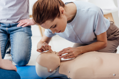 woman practicing cpr technique on dummy during first aid trainingの写真素材
