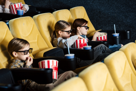 cute friends watching movie and eating popcorn in cinemaの写真素材