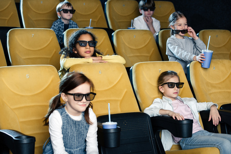 smiling multicultural friends in 3d glasses watching movie in cinemaの写真素材
