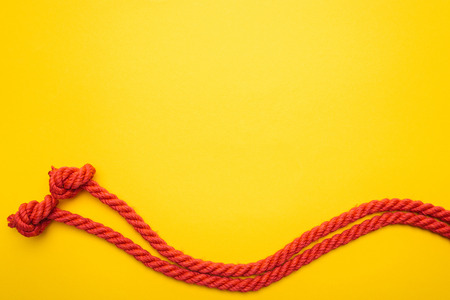 red jute waved ropes with knots isolated on orangeの写真素材