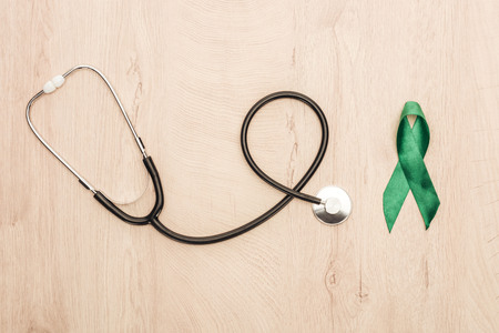 top view of stethoscope and green ribbon on wooden backgroundの写真素材