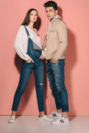 brunette and beautiful girlfriend in denim overalls and handsome boyfriend with hands in pocketsの写真素材