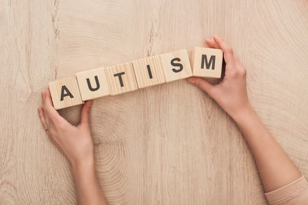 cropped view of woman holding wooden cubes with autism letteringの写真素材