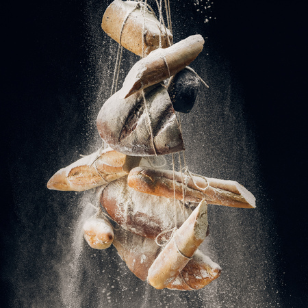 white flour and bread and baguettes on ropes on black backgroundの写真素材