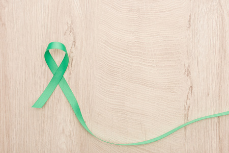 top view of green and colorful ribbon on wooden background with copy spaceの写真素材
