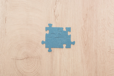top view of blue puzzle pieces connected on wooden tableの写真素材