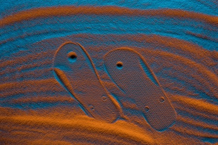 top view of flip flops mark on textured sand with color filterの写真素材