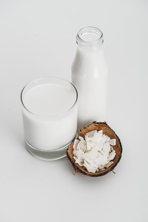 organic vegan coconut milk in glass near coconut chips on grey backgroundの写真素材