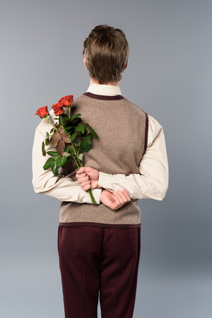 back view of man holding bouquet of roses behind backの写真素材