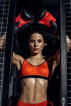 Attractive boxer standing with hands up near wire netting and looking at cameraの写真素材
