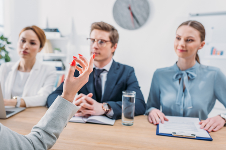 selective focus of female hand gesturing near recruiters during job interviewの写真素材