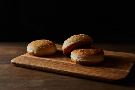 Fresh delicious buns with sesame on wooden chopping board isolated on black backgroundの写真素材
