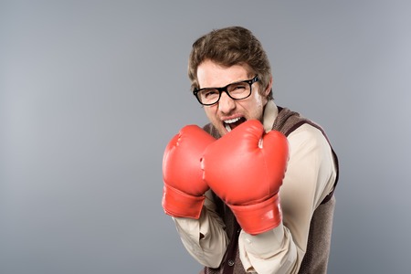 aggressive man in glasses and boxing gloves screaming on grey backgroundの写真素材