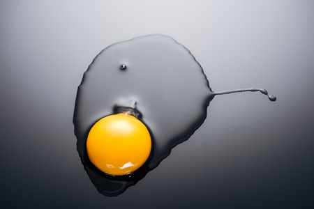 close up of raw smashed egg with yolk and protein on black backgroundの写真素材