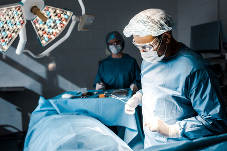 Selective focus of surgeon in uniform and medical cap doing operationの写真素材