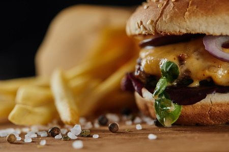 Selective focus of salt and tasty burger with meat and cheese on wooden surfaceの写真素材