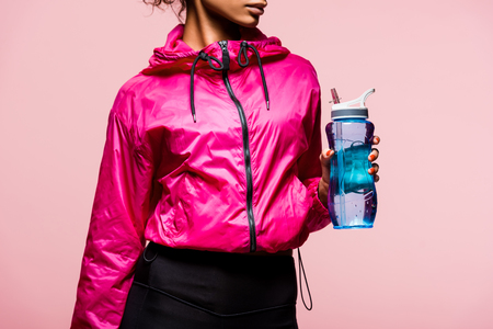 Cropped view of African American sportswoman with sport bottle isolated on pink backgroundの写真素材