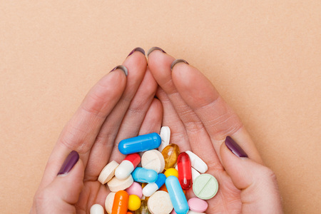 Partial view of woman holding colorful pills in hands on brownの写真素材