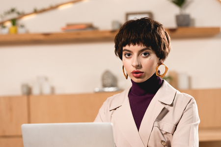 beautiful businesswoman looking at camera while sitting in cafeteriaの写真素材