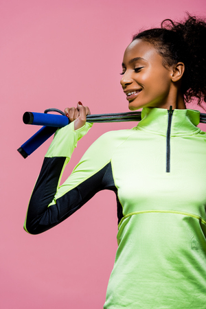 beautiful african american sportswoman posing with skipping rope isolated on pinkの写真素材