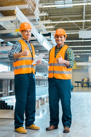 Cheerful multicultural workers smiling and showing thumbs upの写真素材