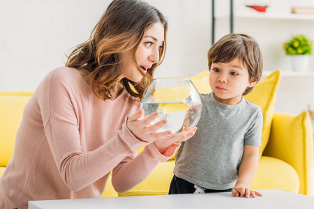 Pretty smiling mother showing fish bowl to adorable sonの写真素材